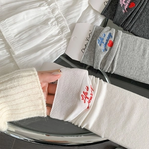 Detail of white knitted mid-calf socks showing breathable texture and heart embroidery