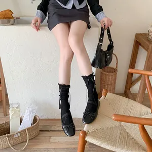 Détail de chaussettes Lolita en dentelle noire avec nœuds en satin et ballerines