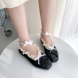 Top view of black ballet flats with white lace trim and ankle ribbons on model feet