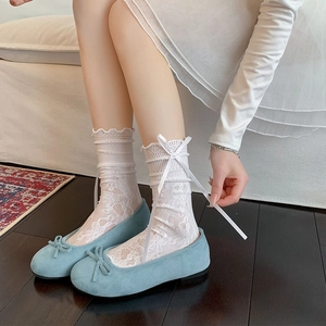 Détail de chaussettes en dentelle blanche à nœuds et ballerines en daim bleu clair