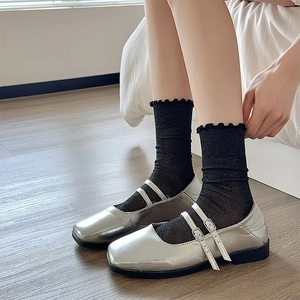 Detail of silver Mary Jane shoes with double straps and black ruffle trim socks