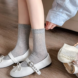 Détail de chaussettes en maille grise à motifs de cœurs et chaussures Mary Jane au sol