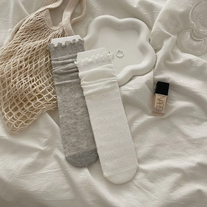 Detail of cotton mesh socks with bow patterns, ruffled edges, in white and grey