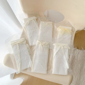 Close-up of Lolita mesh socks in frosted zipper packaging with cream silk bows