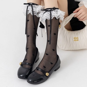 Close-up of Lolita knee-high socks with white lace trim, black bows, and heart patterns