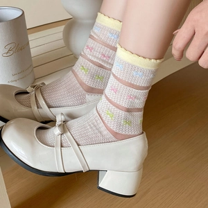 Detail of sheer mesh socks with colorful bow patterns and yellow lettuce edge cuffs