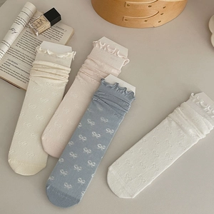 Close-up of mesh knit socks with bow jacquard patterns and delicate ruffled cuffs