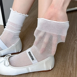 Close-up of white mesh lace socks with ruffle cuffs paired with white satin flats