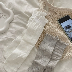 Detail of ruffle cuffs and bow patterns on breathable knit mesh socks in a lifestyle setting