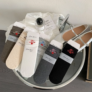 Detail of six mid-tube socks in assorted colors with heart embroidery and stylish packaging