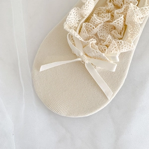 Detailed close-up of ballet-style lace boat socks with silk bow and knit texture