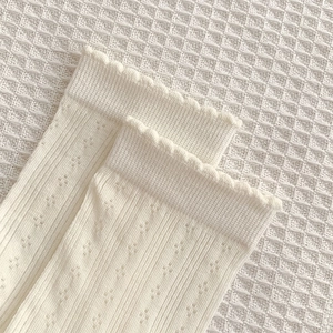 Détail de chaussettes en maille crème avec bords festonnés et texture ajourée élégante