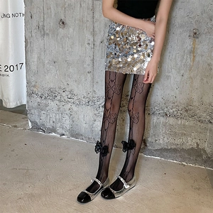 Detail of black lace fishnet tights with 3D bow accents and elegant pattern