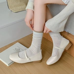 Nahaufnahme von cremefarbenen Mary Janes mit weißen vertikal gestreiften Strick-Socken