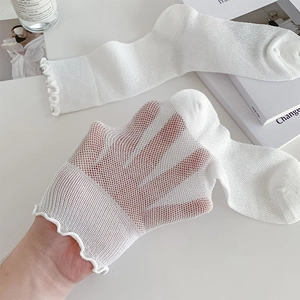 Detail of white mesh socks with elegant ruffle cuffs and breathable hollow knit texture