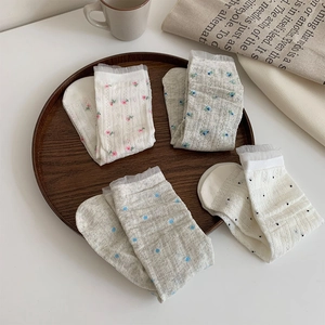 Close-up of four pairs floral mesh socks with white lace trim in a wooden tray