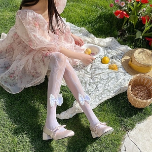 Detail of white lace mesh tights with bow accents paired with pink Mary Jane shoes