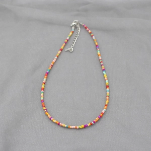Detail of colorful seed bead necklace featuring a silver lobster clasp and extension chain