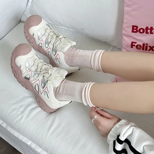 Detail of beige and pink hollowed sport sandals with breathable mesh on white sofa