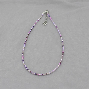 Colorful bohemian beaded necklace with purple and white beads featuring an adjustable silver clasp