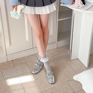 Dettaglio di ballerine argento con fiocchi e calze grigie con pizzo bianco
