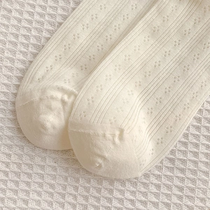 Détail de chaussettes en coton crème avec motif diamant ajouré et texture côtelée