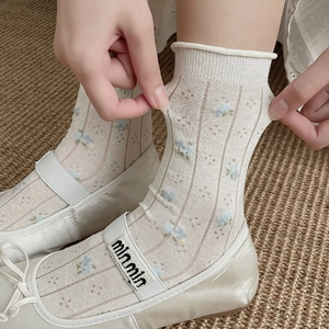 Detail of white lace socks with floral patterns and high elasticity on model