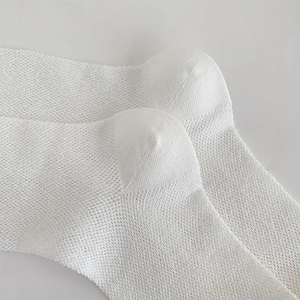 Close-up of white breathable mesh socks with reinforced heel and knitted texture