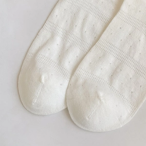 Close-up of white breathable mesh knit socks with delicate hollowed-out dot patterns