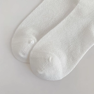 Close-up of white mesh breathable socks showing fine grid weave and reinforced toe seam
