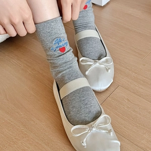 Detail of light gray cotton socks with Life is a journey blue embroidery and red heart