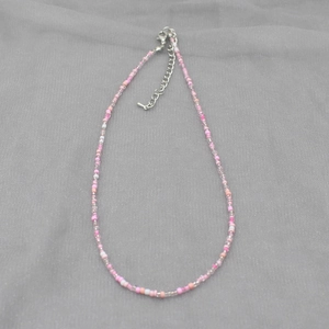 Detail of pink and white colorful beaded necklace with silver lobster clasp and extension chain
