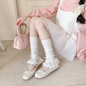 Close-up of ballet flats with silk bows and white lace hollow-out knee-high socks