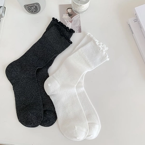 Detail of white and black ruffle cuff mid-calf socks in a minimalist lifestyle setting