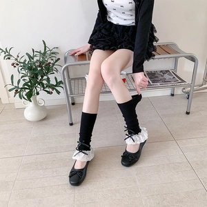 Detail of ballet style ribbed socks with white lace trim and black bow accents