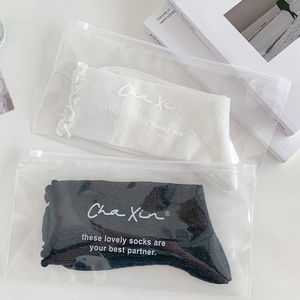 White and black crew socks with ruffle edges in premium frosted zipper bag packaging