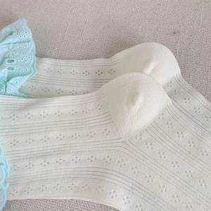 Dettaglio calzini in cotone beige con pizzo blu e trama a rete traforata