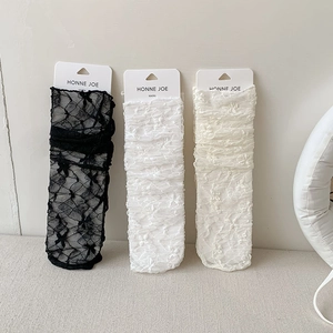Detail of ballet style white floral lace and black bow socks with branded packaging