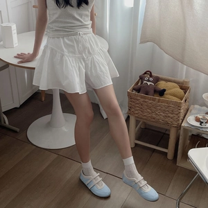 Close-up of white layered ballet-style ruffled socks paired with light blue velcro sneakers