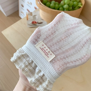 Detailed close-up of white lace mesh socks with beige plaid trim and woven label detail