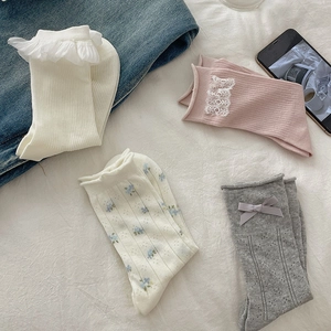 Detailed texture of white lace ruffle socks and grey ballet style bow knit hosiery
