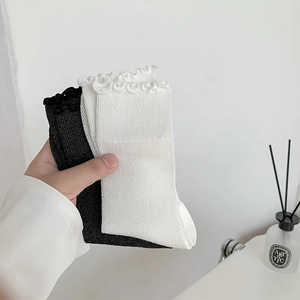 Detailed view of ruffle cuff cotton socks in black and white with soft knitted texture
