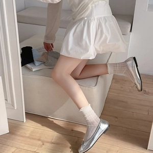 Detailed shot of white diamond mesh knee high socks with ruffle cuffs and silver ballet flats