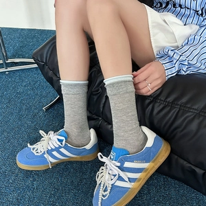 Dettaglio sneaker in camoscio blu con strisce bianche e lacci decorati con perle