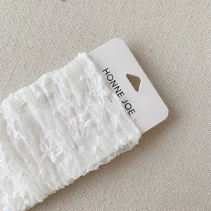 Detailed macro view of white floral lace texture on socks with brand display card