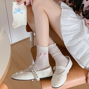Detailed view of beige ribbed socks with ruffled edges and pink checkered bows