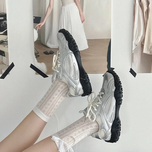 Dettaglio delle sneakers argento vintage con calze in pizzo e rete in una posa dinamica