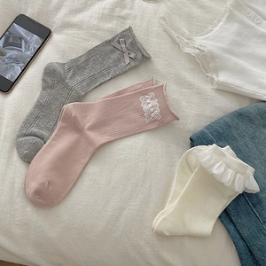 Close-up of white lace trim socks and grey silk bow detail on cotton ribbed fabric