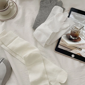 Detail of white ribbed Tabi socks and grey crew socks in a cozy lifestyle setting