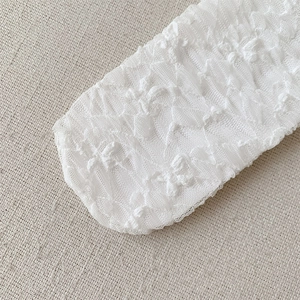Close-up of intricate white lace floral pattern and delicate mesh texture on ballet socks